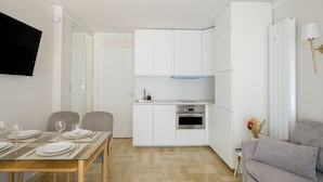 A modern kitchen with white cabinets, a dining table set with plates and glasses, and a sofa in the living area. - Apartment with Private Terrace, Wi-Fi and Air Conditioning (Nice)