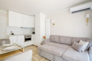 Un soggiorno moderno e minimalista con angolo cottura, divano e zona pranzo.