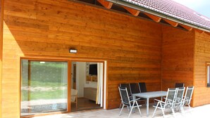A wooden cabin with a sliding glass door leading to an interior space, a patio table with chairs, and a tiled roof. - Vacation home Dola II in Bohemian Paradise with pool (Mírová pod Kozákovem)