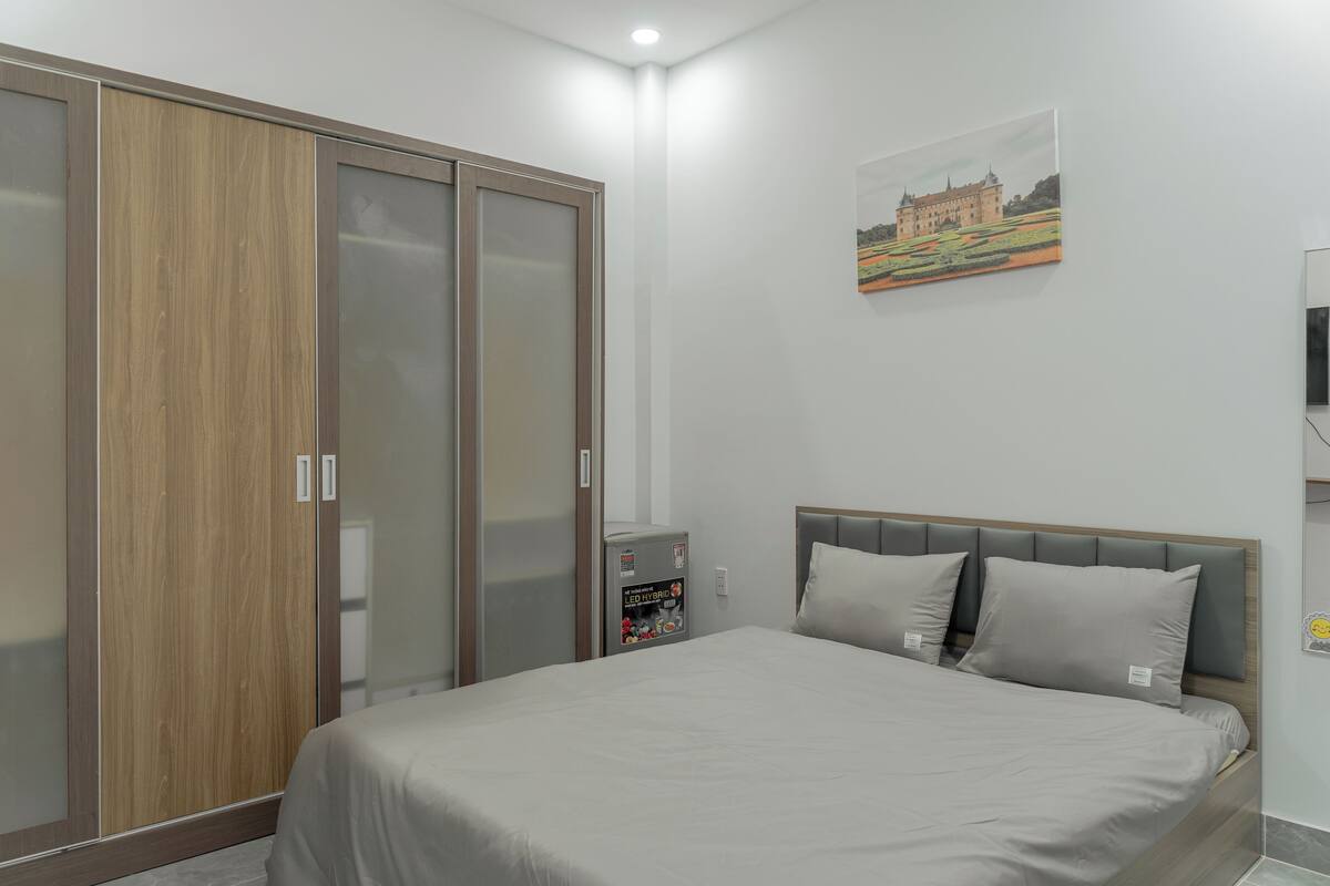 Ein Schlafzimmer mit einem Bett, einem Kleiderschrank, einem kleinen Kühlschrank und einem Bild an der Wand.