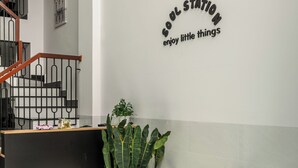 A reception area with a marble table, wooden chairs, a potted plant, and a wall sign. - Soul Station Studio Hotel II (Ho Chi Minh City)