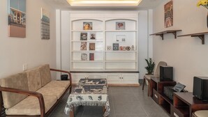 A living room with a sofa, a coffee table, a TV stand, and a ceiling fan. - Soul Station Studio Hotel II (Ho Chi Minh City)