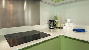 A modern kitchen with a black induction cooktop, green cabinets, and a coffee maker. - 3BR PoolVilla 7 Mins to Nai Harn V108 (Rawai)