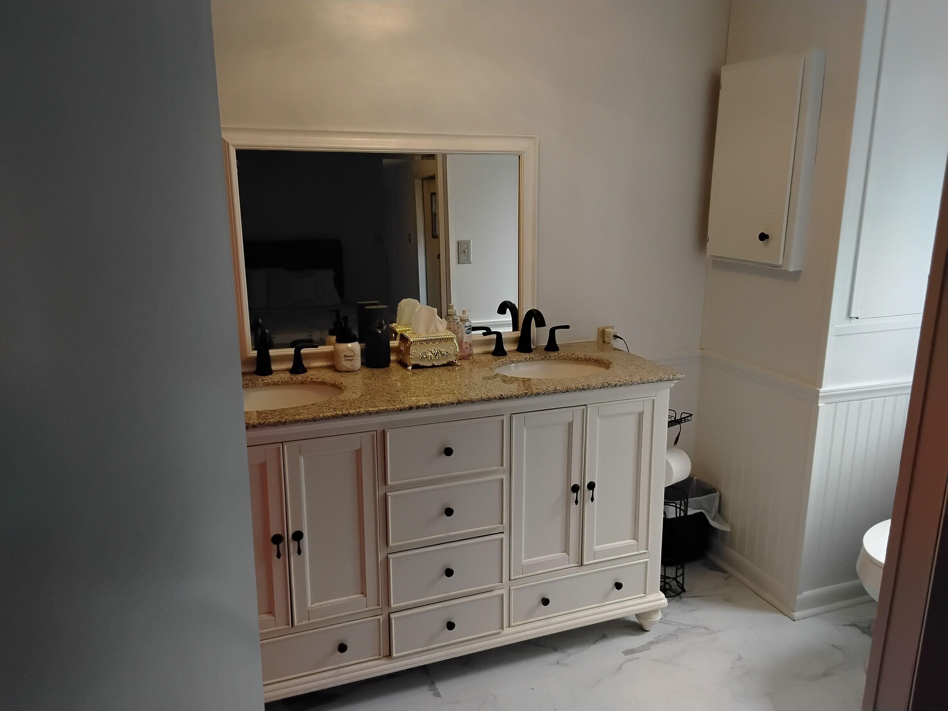 Ein Badezimmer mit einem Waschbecken-Doppelwaschplatz, einem Spiegel und einer Toilette.