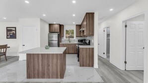 A modern kitchen with wooden cabinets, a stainless steel refrigerator, and a central island. - Spacious home with 6 Beds (Brampton)