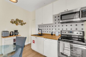 A compact kitchen with a microwave, stove, and dishwasher, a coffee maker, and a toaster on the counter.