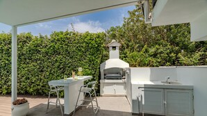 An outdoor kitchen area with a grill, bar stool, and sink. - La Casa De Louie Villa (Sotira)