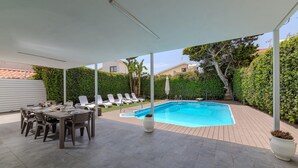 A covered outdoor area with a pool, lounge chairs, and a dining table. - La Casa De Louie Villa (Sotira)