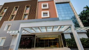 Et moderne hotel med et tydeligt skilt, der viser "J.K. Residency", en glasklædt indgang og en veldefineret facade med mange vinduer.