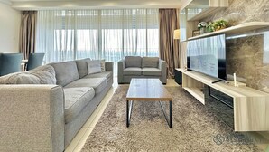 Una sala de estar moderna con sofá, sillón, mesa de centro, televisor y ventilador de techo.