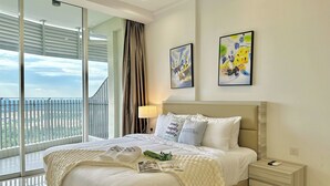 Una habitación de hotel con una cama grande, una mesita de noche, una lámpara y dos cuadros en la pared.
