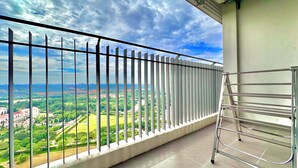 Un balcón con barandilla de metal que da a un paisaje verde y edificios.