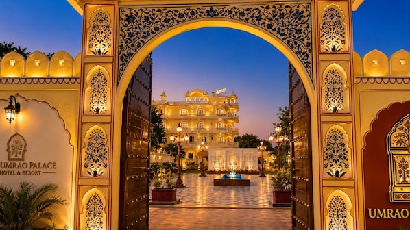 A entrada do Hotel & Resort Umrao Palace, com arcos ornamentados e um pátio bem iluminado.