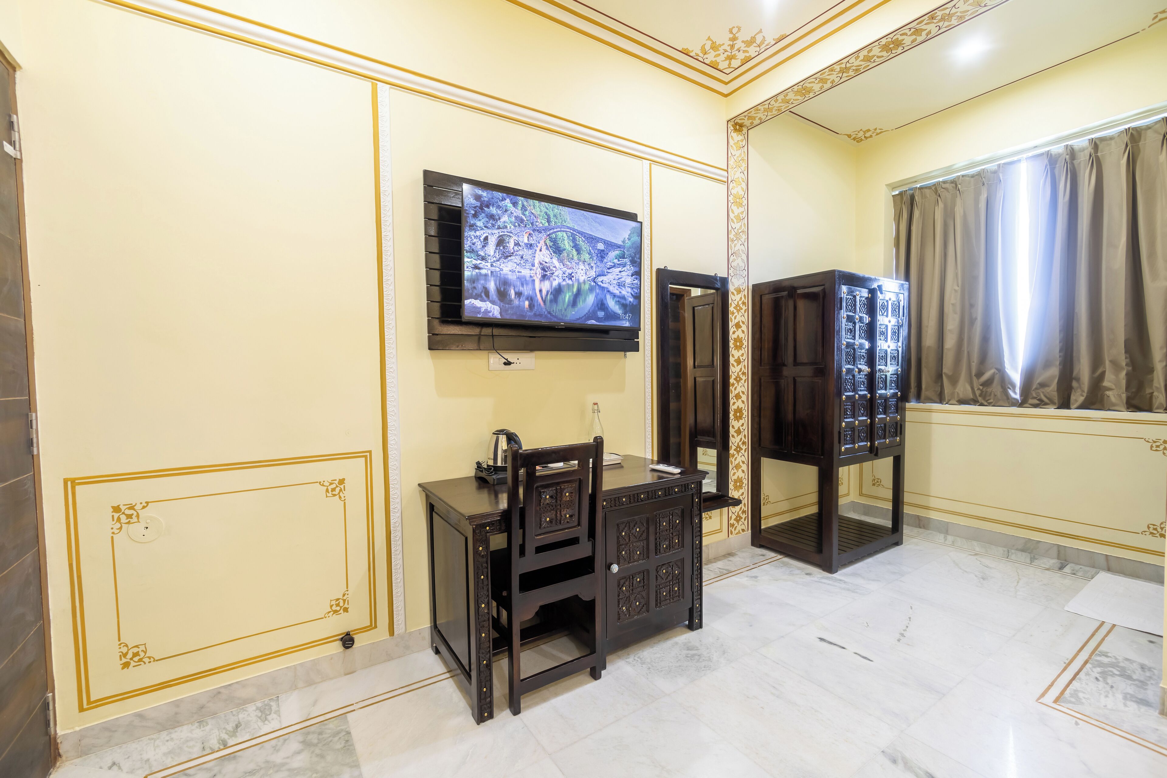 Una habitación con televisión montada en la pared, un armario de madera y un espejo.