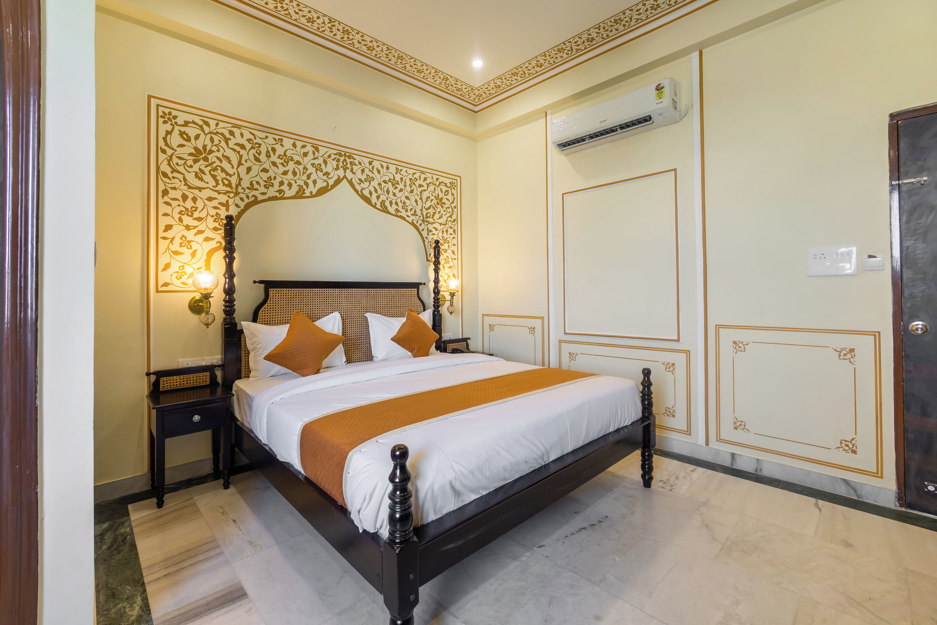 A neatly arranged bedroom with a large bed, a bedside table, an air conditioning unit, and a wardrobe.
