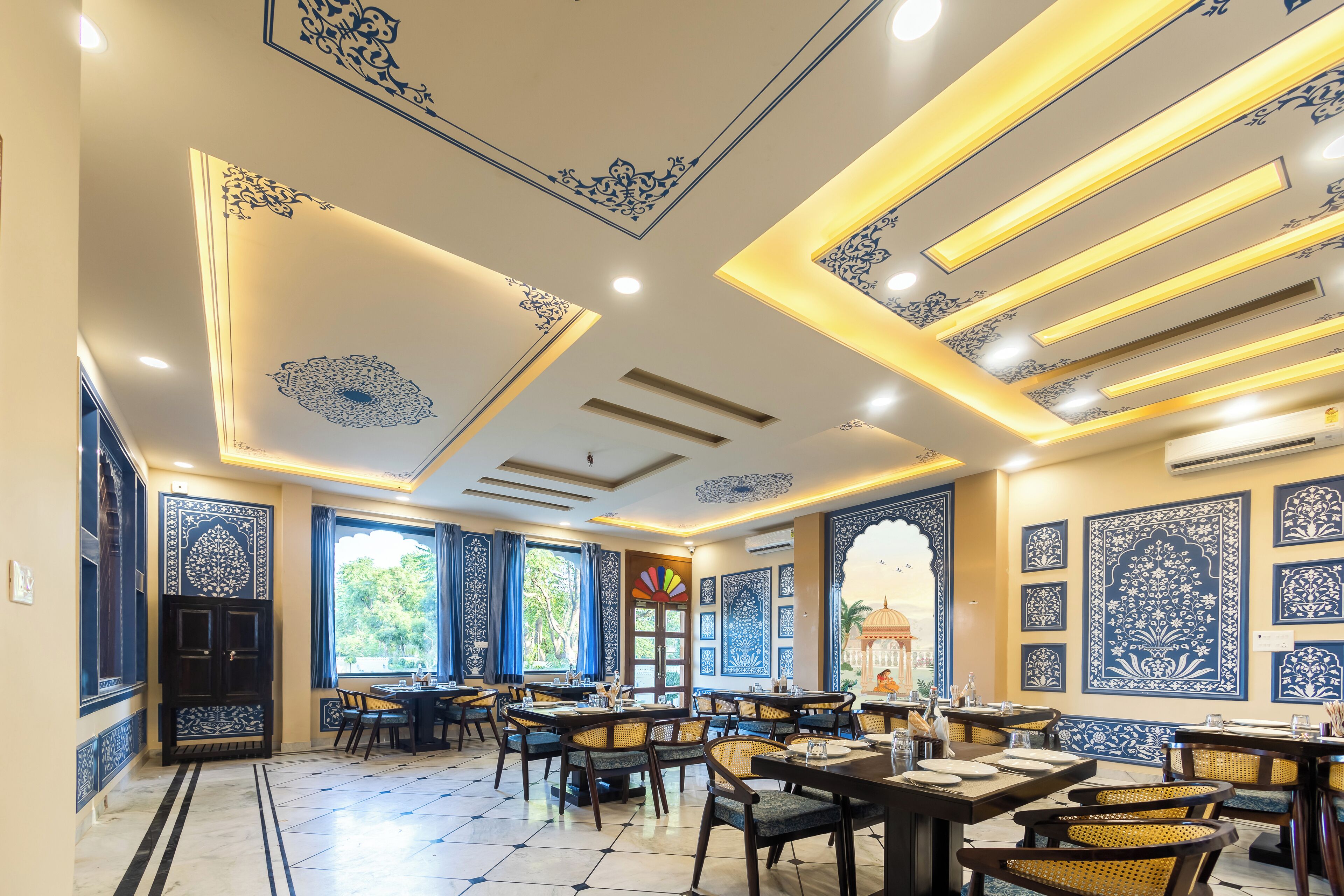 A restaurant with traditional decor, featuring patterned walls and ceiling, and multiple dining tables and chairs.