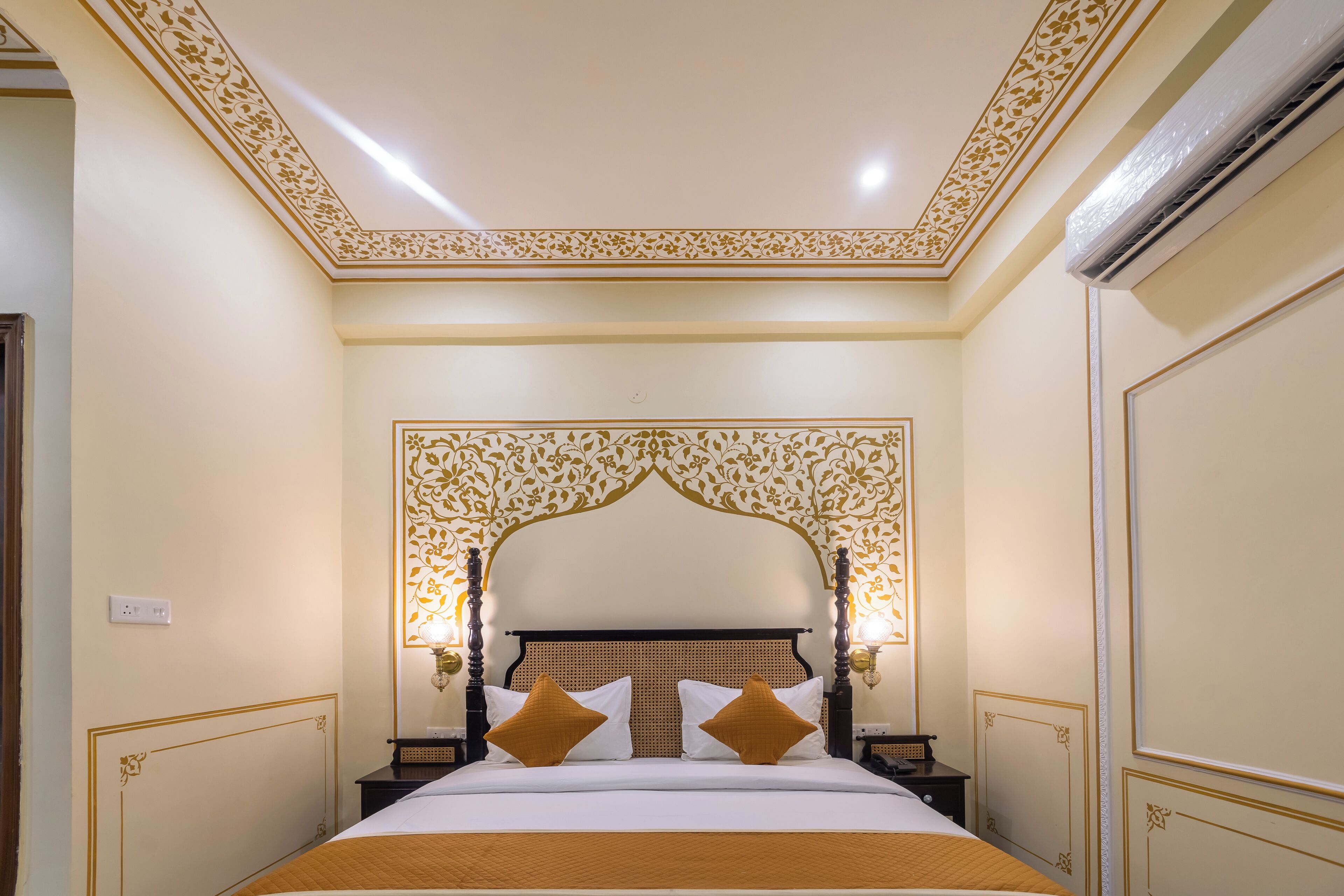 Ein Hotelzimmer mit einem großen Bett, einem aufwendigen Kopfteil und dekorativen Wandmustern.