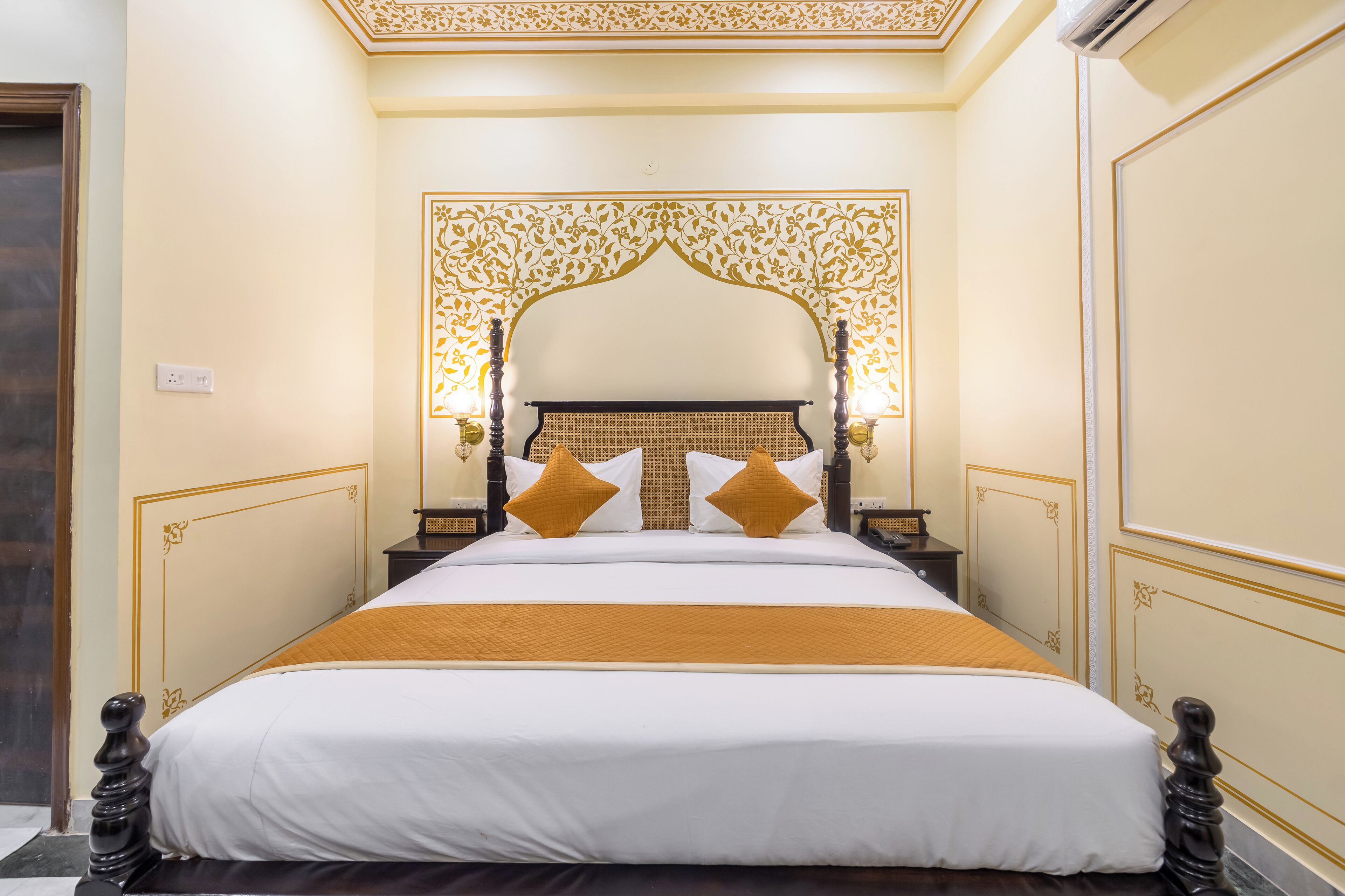 A neatly made bed with a headboard, two bedside tables, and a decorative wall panel.