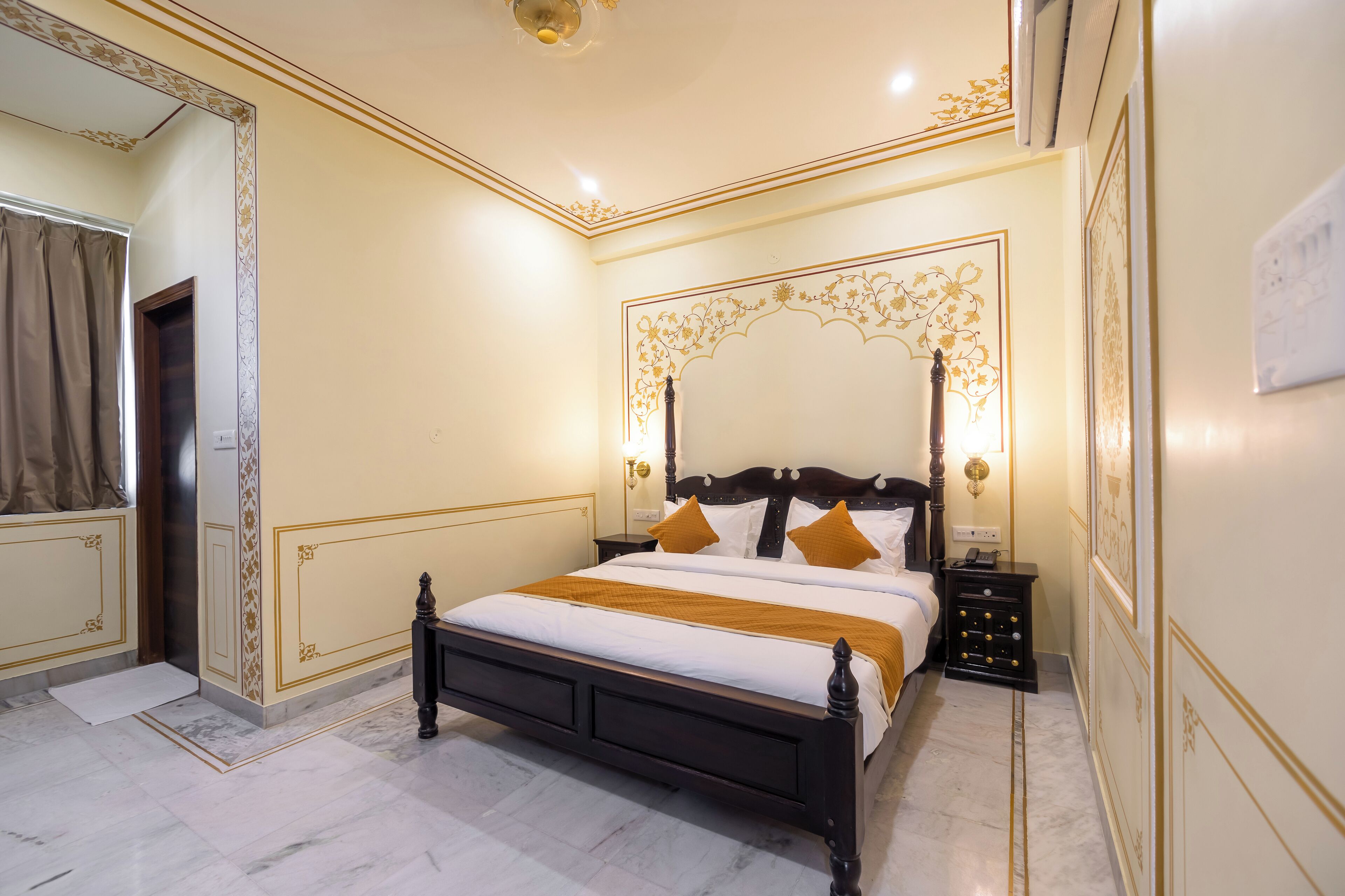 A hotel room with a large bed, a nightstand, a mirror, and a wall with decorative patterns.