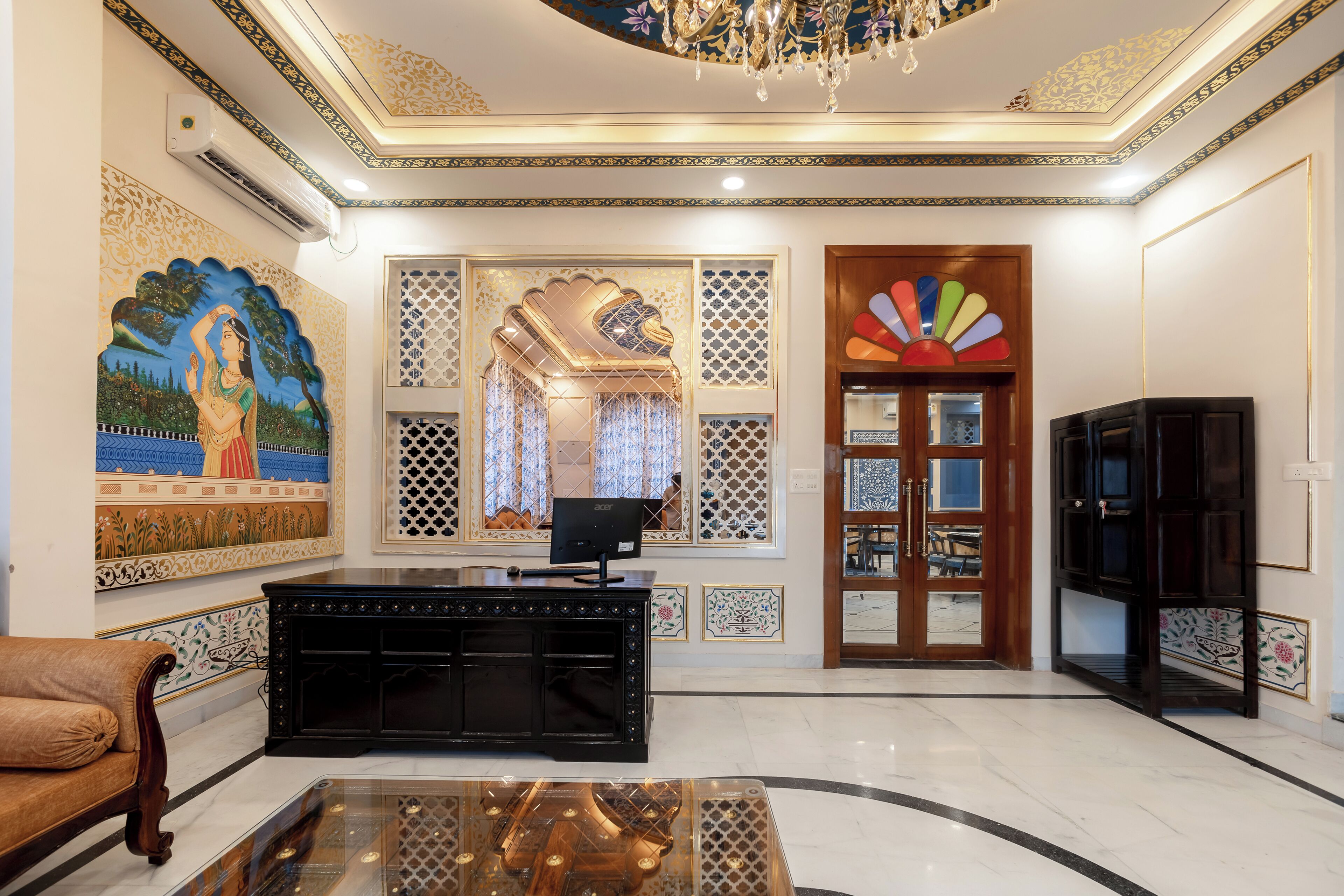 A luxurious lobby with a marble floor, a black reception desk, a large painting, and a decorative chandelier.
