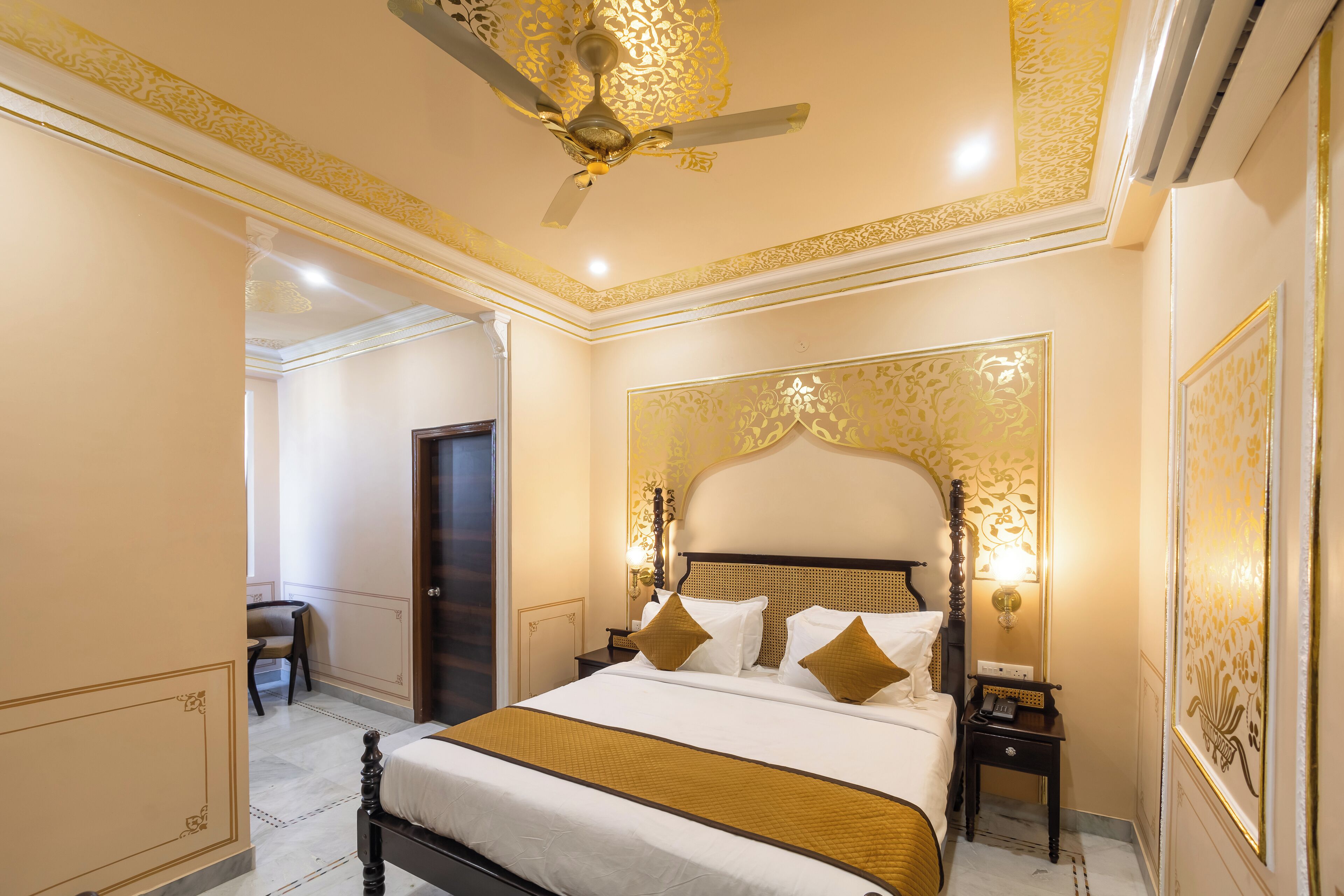 A hotel room with a large bed, a ceiling fan, a nightstand, and a door.