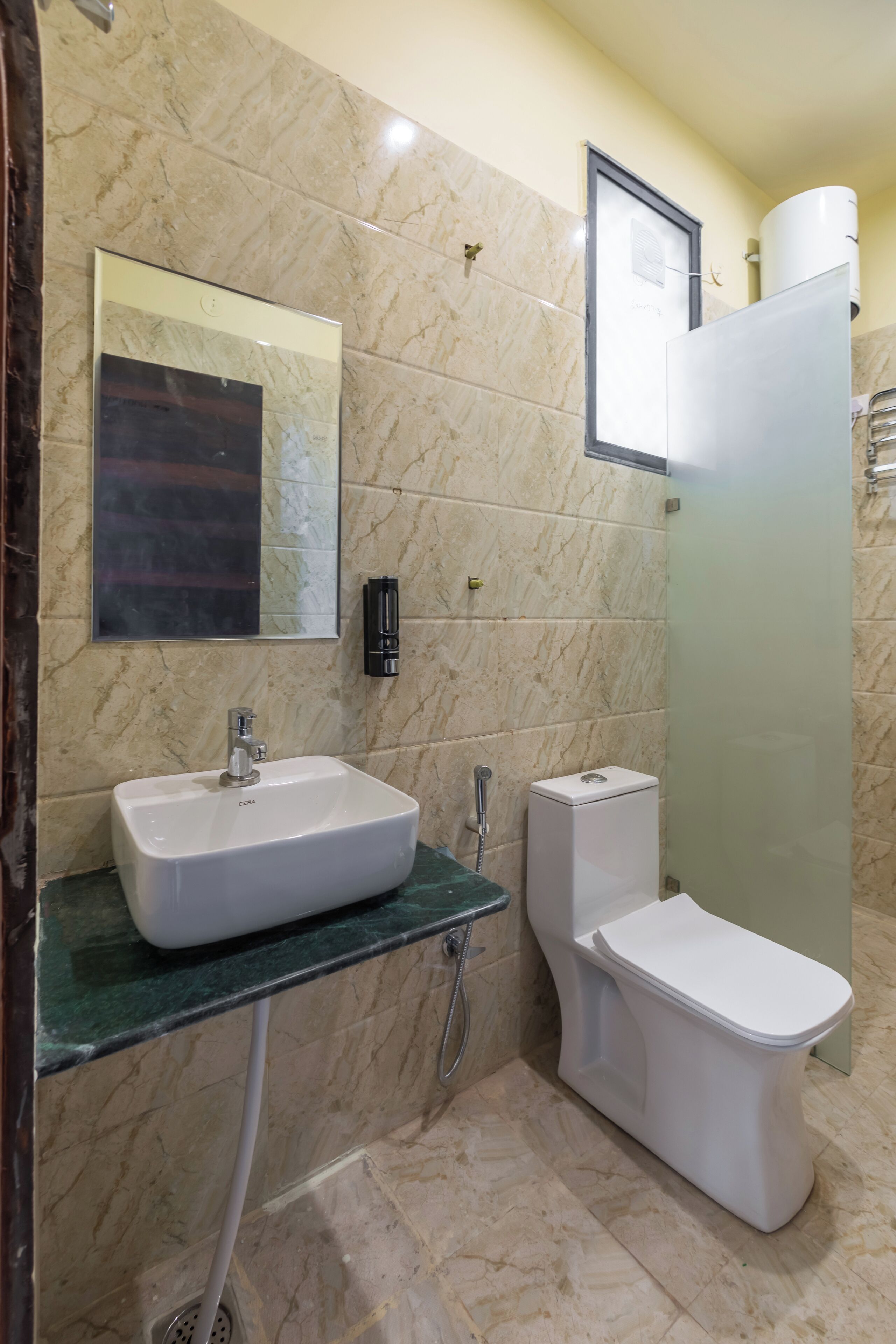 A bathroom with a marble wall, a sink, a toilet, and a shower enclosure.