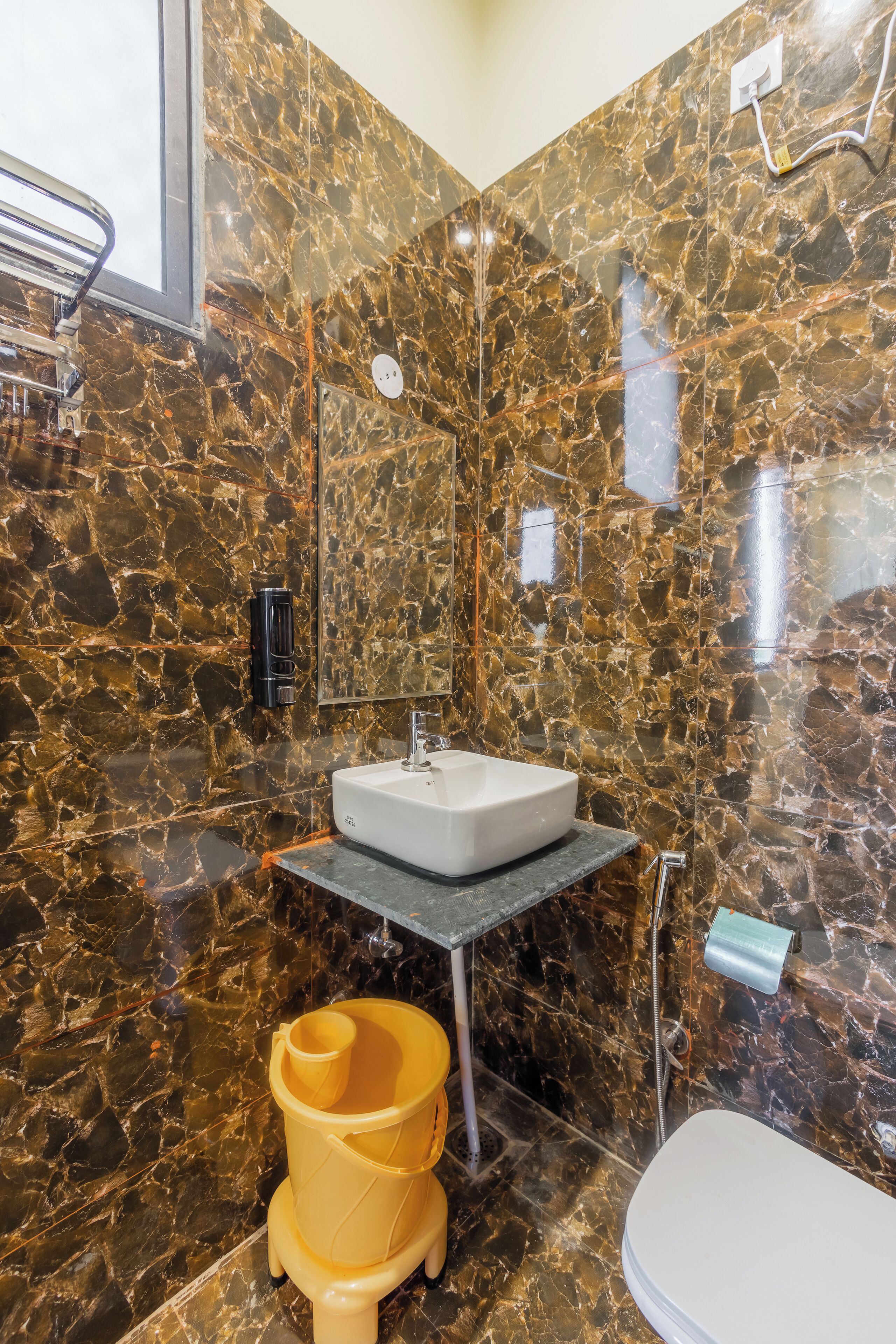 Ein Badezimmer mit Marmorwand, Waschbecken, Toilette und einem gelben Bidet.