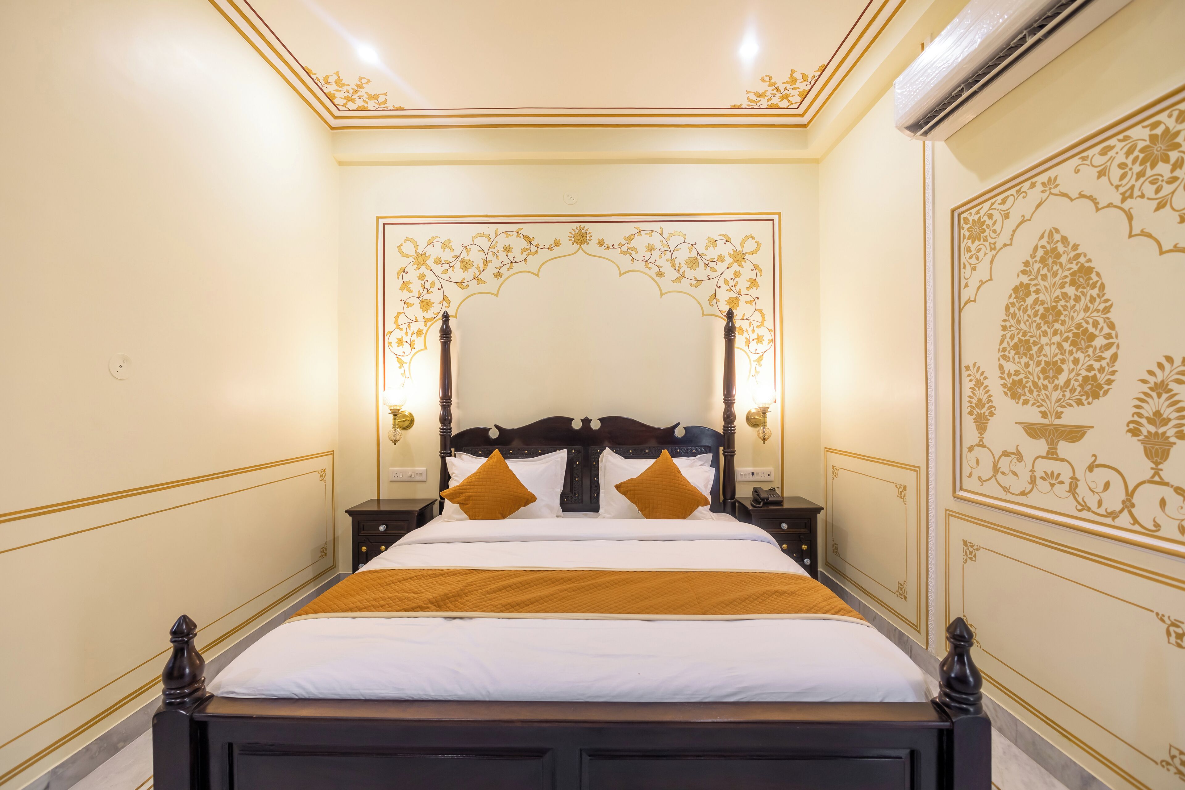 A neatly made bed with a wooden headboard, two bedside tables with lamps, and ornate wall decorations.