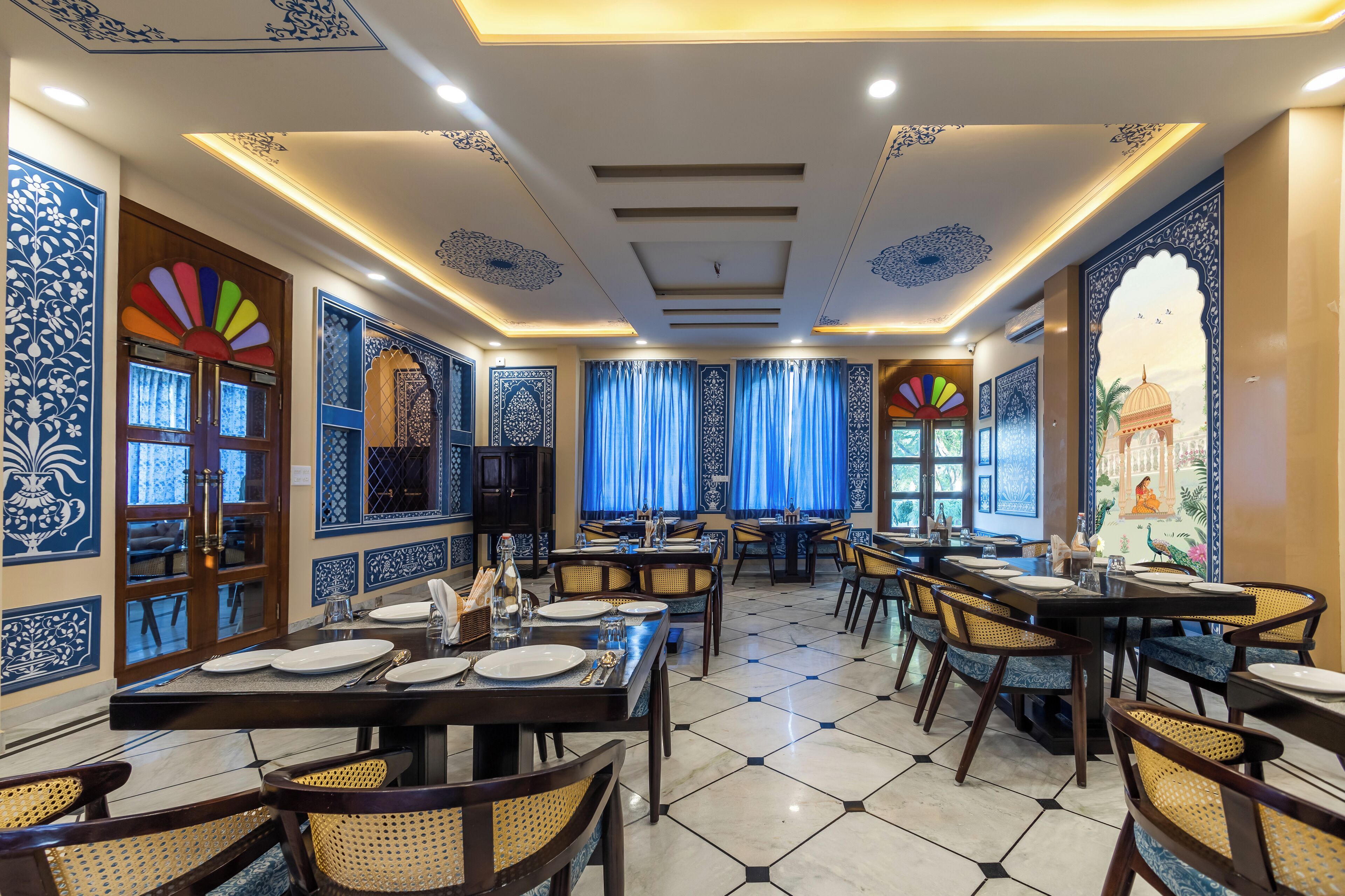 A restaurant with multiple tables and chairs, blue and white patterned walls, and a tiled floor.