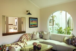 A living room with a sofa, a coffee table, a framed picture, and a round window.
