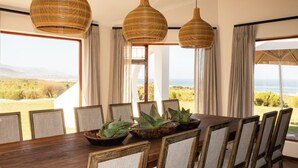 Een eetgedeelte met een houten tafel, stoelen en geweven hanglampen.