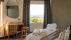 Een slaapkamer met een bed, een bureau, een stoel, een spiegel en een raam met uitzicht.