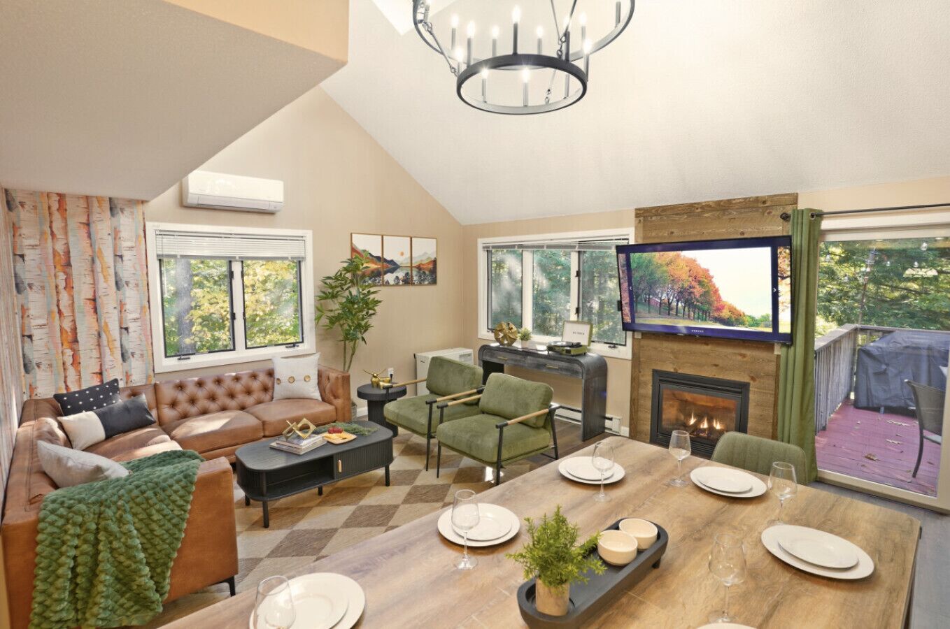 A spacious living room with a fireplace, a dining area with a wooden table set for four, and a comfortable seating area with a sofa and armchairs.