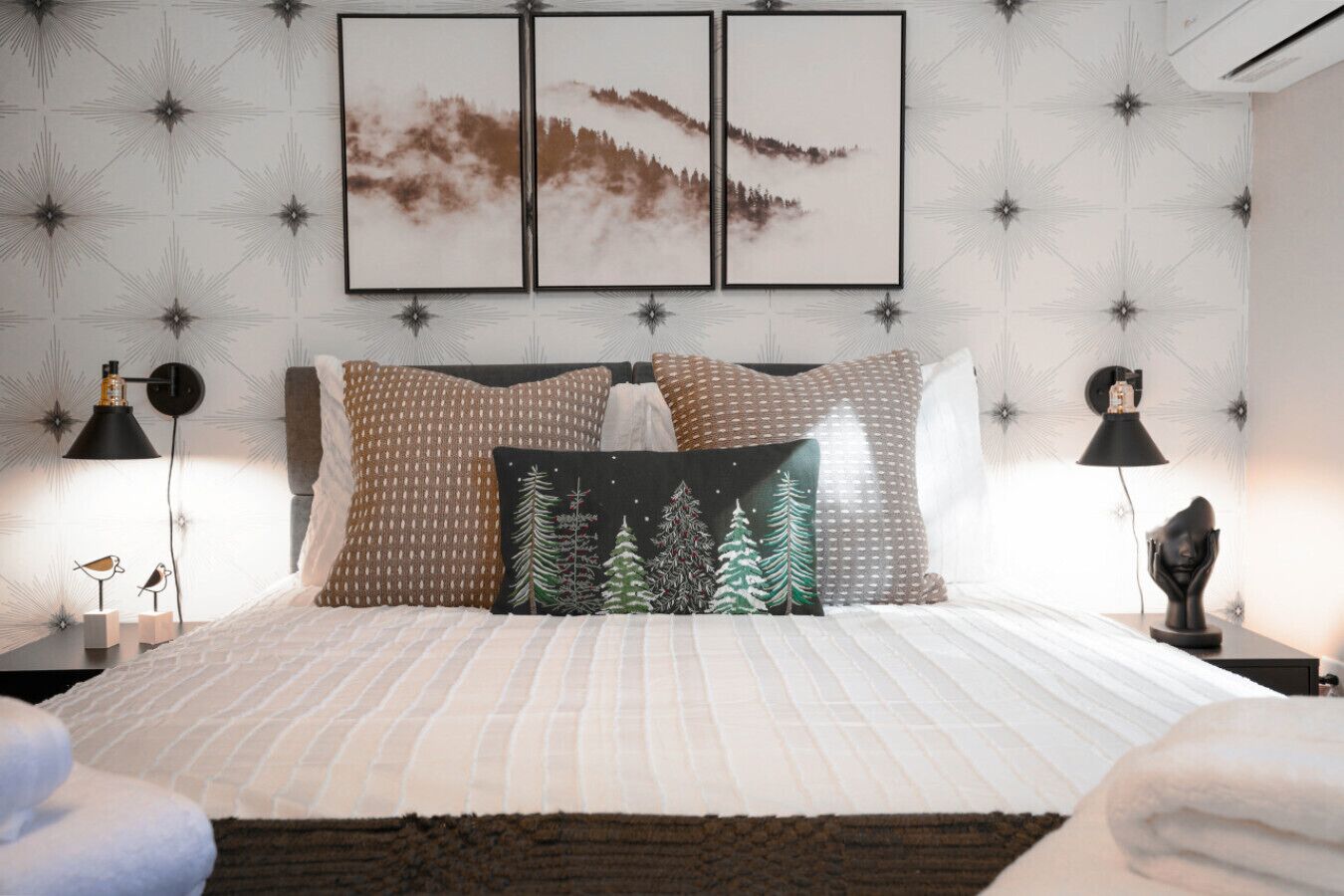 A neatly arranged bedroom with a bed, pillows, a nightstand, a lamp, and wall art.
