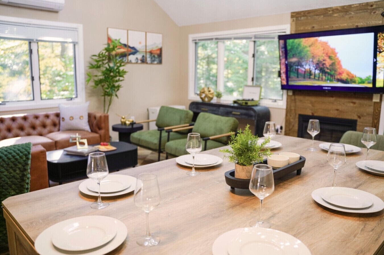 A dining area with a wooden table set for a meal, surrounded by green chairs and a sofa.