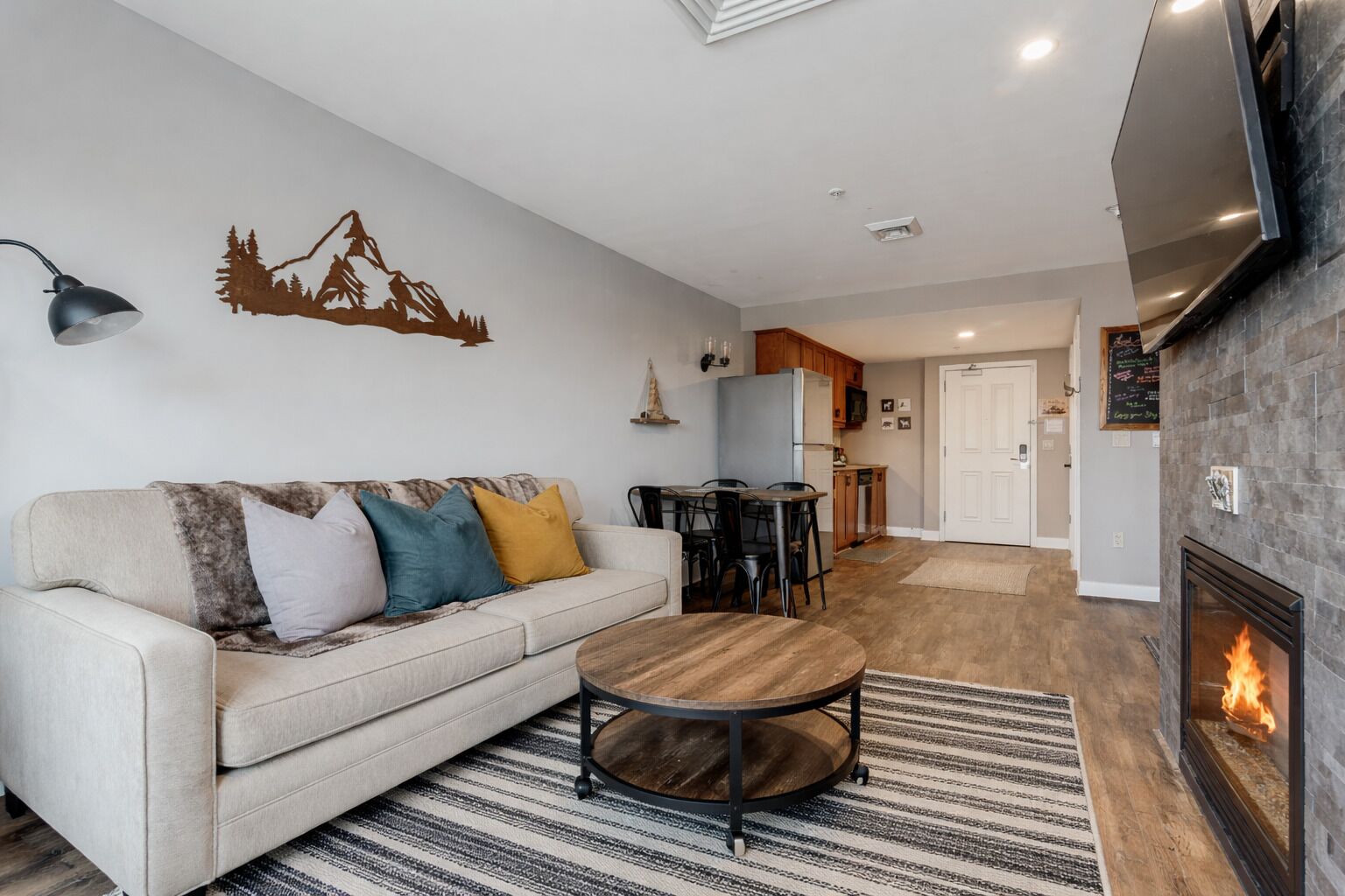A living room with a sofa, coffee table, fireplace, and a dining area with chairs and a table.