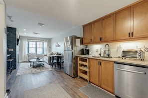 A modern kitchen with wooden cabinets, stainless steel appliances, and a dining area with a table and chairs. - Rustic Chic Stays - Walk to Mountain Creek Resort - Waterpark Open Weekends! (Vernon Township)