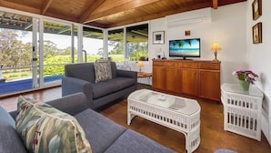 A spacious living area with a wooden ceiling, a television, and a view of the outdoors.