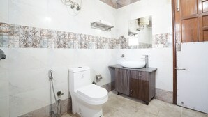 A bathroom with a toilet, sink, and shower. - Hotel Raj Mahal (Gurugram)