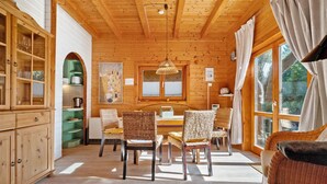 Een houten interieur met een eethoek, rieten stoelen, een tafel en een bank.