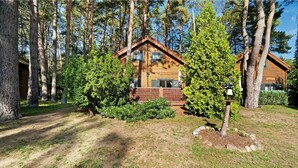 Een chalet omringd door bomen, met een houten gevel en een terras.