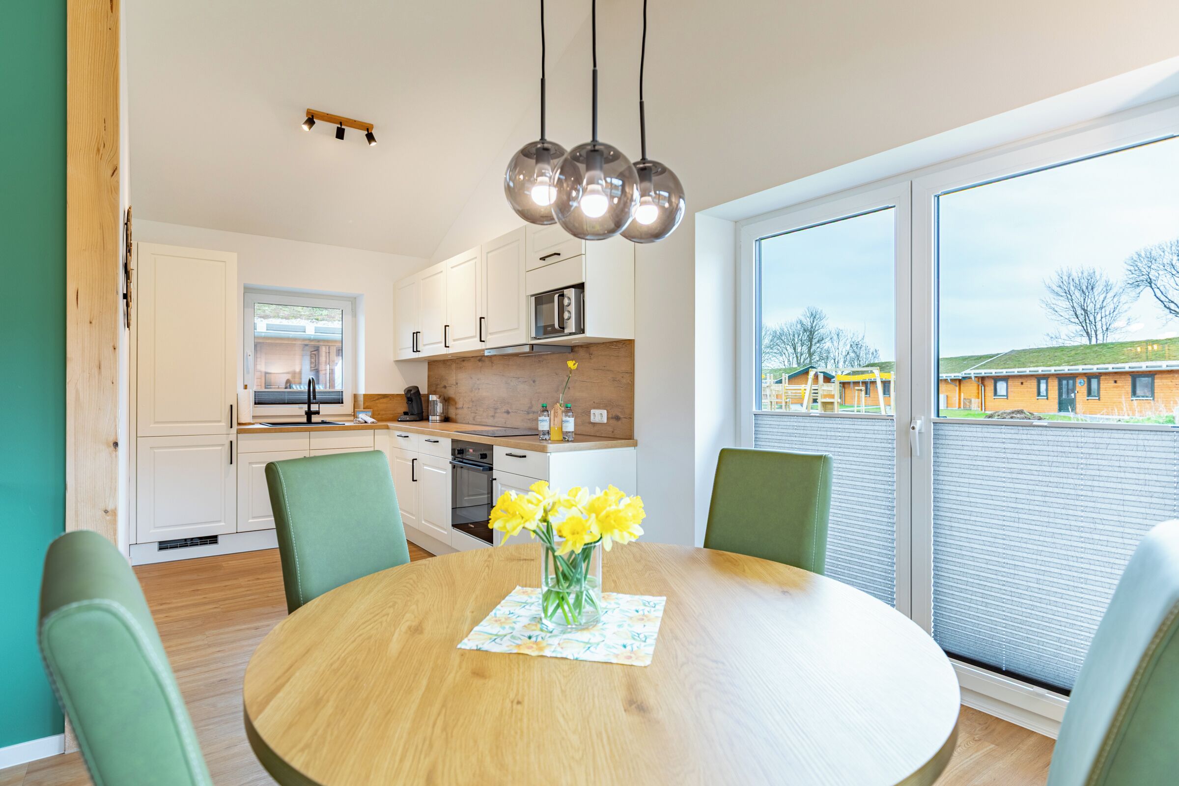 A modern kitchen with white cabinets, a wooden countertop, and a dining area with a round table and chairs.