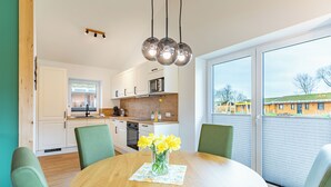 A modern kitchen with white cabinets, a wooden countertop, and a dining area with a round table and chairs. - Vacation home "Huus Plüschmors" in Kating for up to 4 people (Kating)