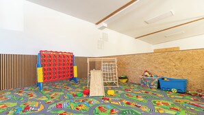 A playroom with a colorful play mat, a climbing net, and various toys. - Vacation home "Huus Plüschmors" in Kating for up to 4 people (Kating)