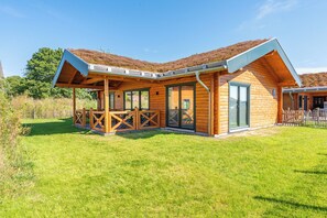 Une cabane en bois dotée d’un patio couvert et de grandes fenêtres.