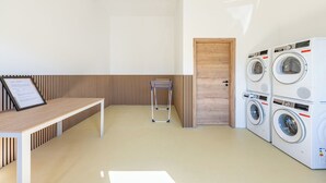 A laundry room with a wooden door, a washing machine, and a drying rack. - Vacation home "Huus Plüschmors" in Kating for up to 4 people (Kating)