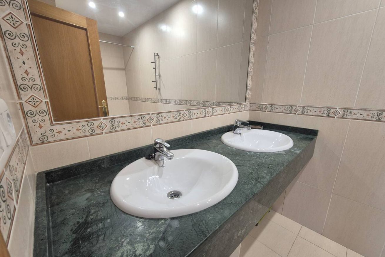 Een badkamer met twee wastafels, een spiegel en betegelde wanden.