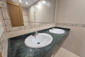 A bathroom with two sinks, a mirror, and patterned tiles.