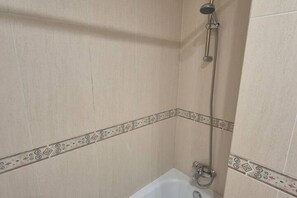 A bathroom with a shower, a bathtub, and decorative tiling.