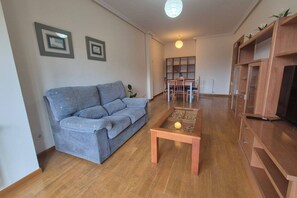 Una sala de estar con sofá, mesa de centro, mueble para televisión y comedor.